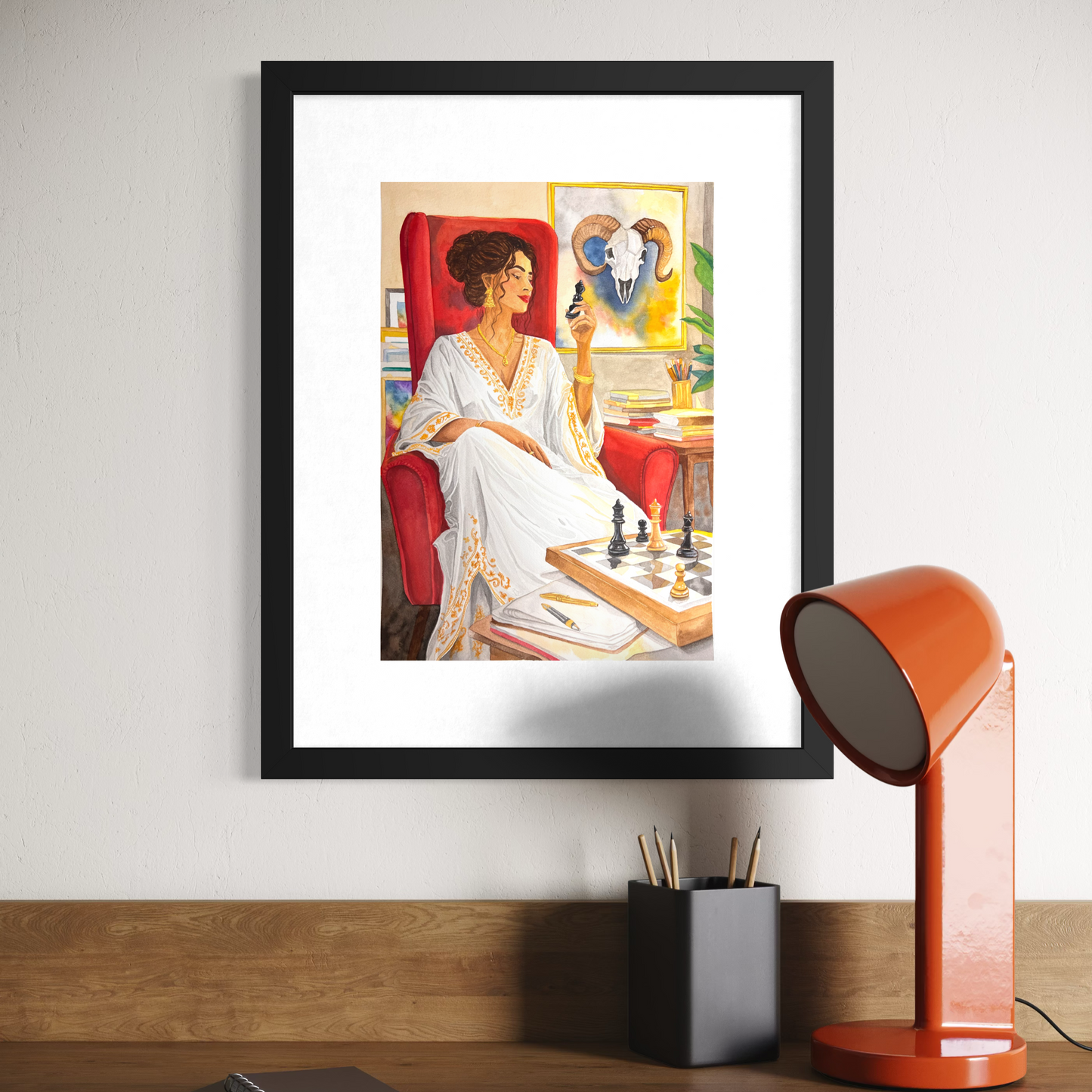 Framed artwork of a woman in a white dress sitting in a chair, placed on a wooden surface with a lamp and books.