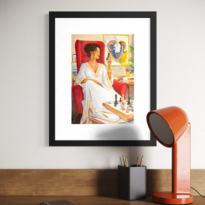 Framed artwork of a woman in a white dress sitting in a chair, placed on a wooden surface with a lamp and books.